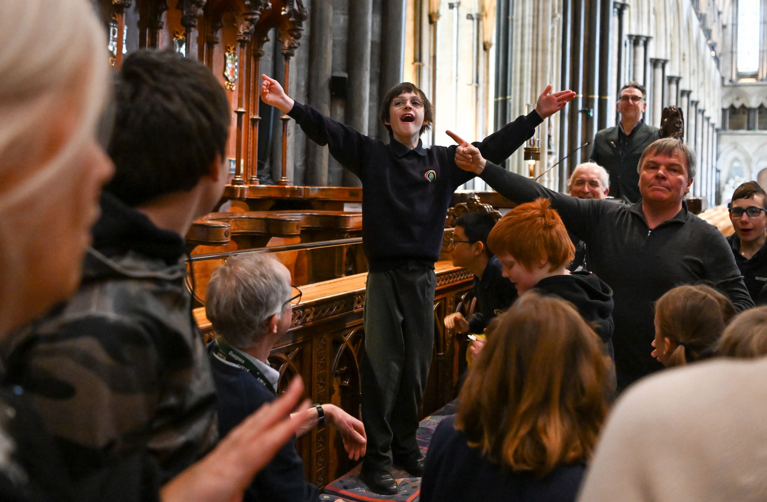 A person standing up in the Cathedral choir surrounded by people