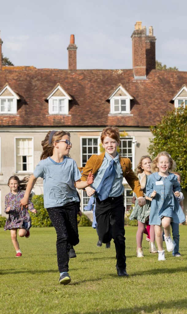 large group of children running and laughing across a lawn