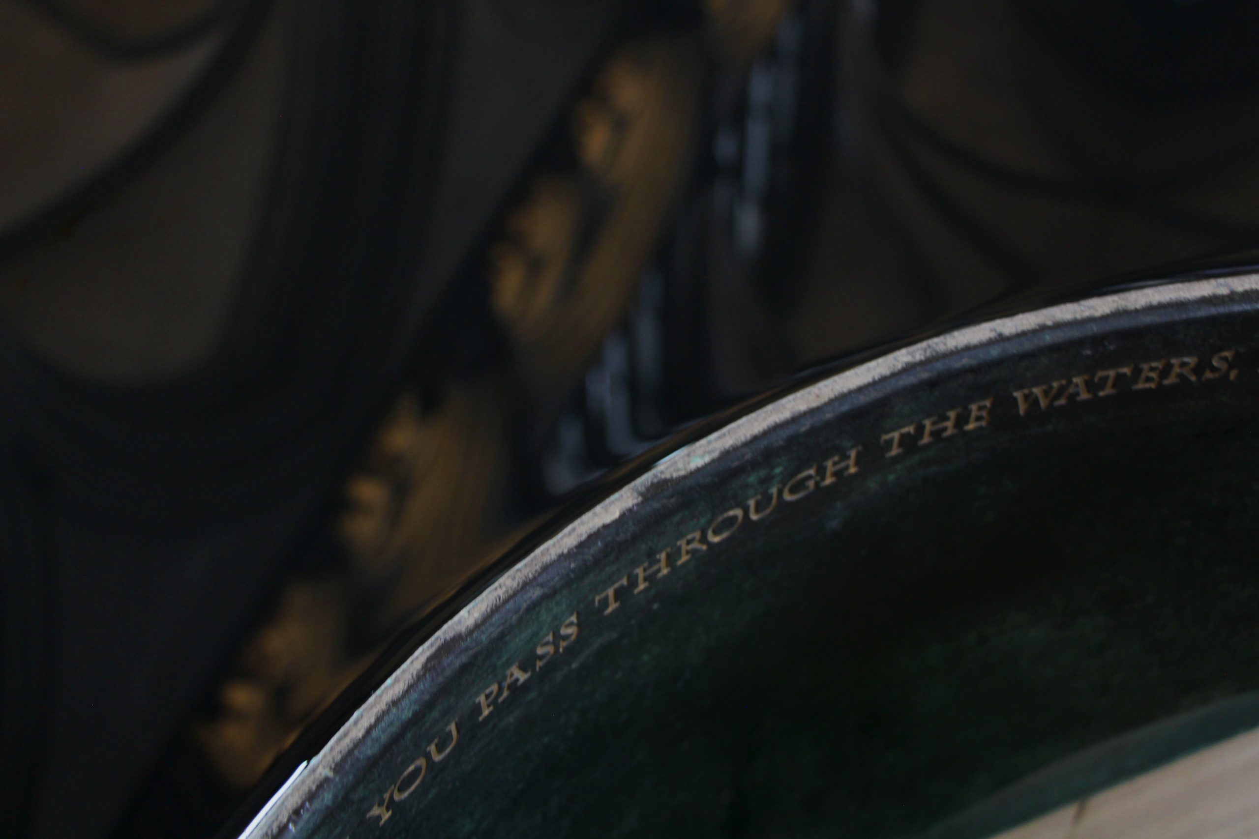 Detail of Salisbury cathedral font showing text inscribed "you pass through the waters"